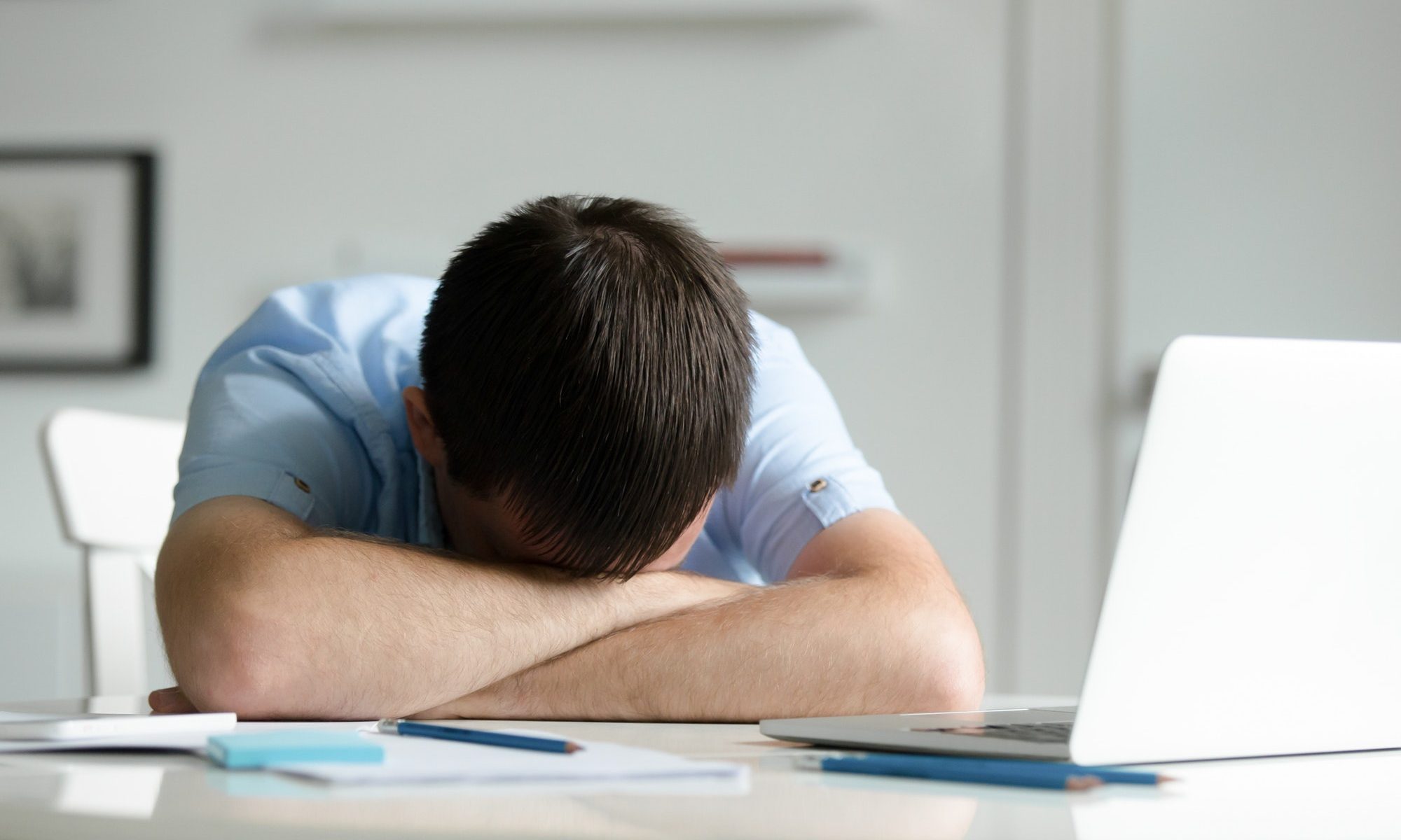 Portrait of a man lying down at desk near laptop